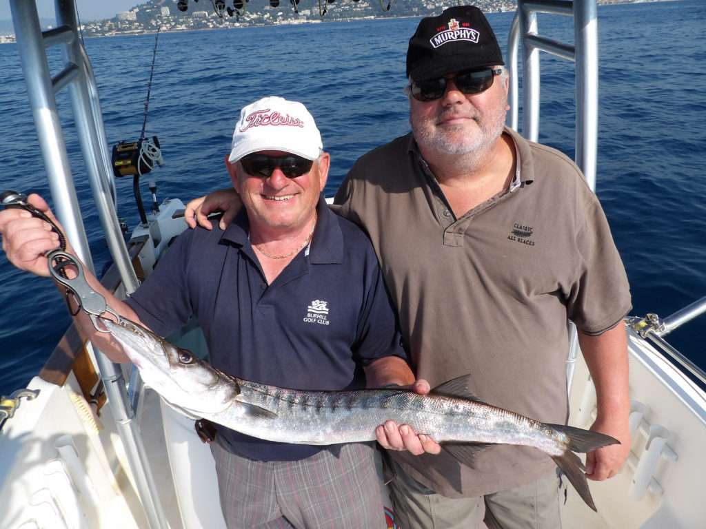 Des clients du guide de pêche Fabien Harbers tenant un beau barracuda avec le fish grip scale luxe