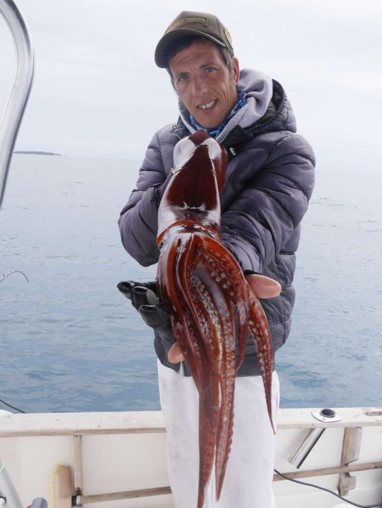 Le moniteur guide de pêche Fabien Harbers avec un gros calamar rouge pris à 500 m de profondeur